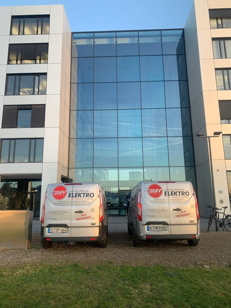 MRV-Elektro: zwei gebrandete Fahrzeuge der eigenen Flotte vor einem Bürogebäude in Aachen